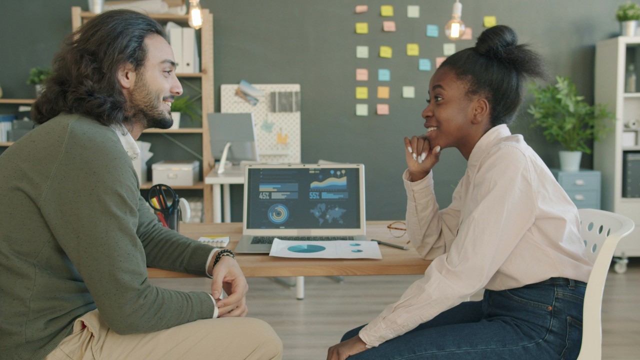 Two Colleagues Discussing Work at a Desk